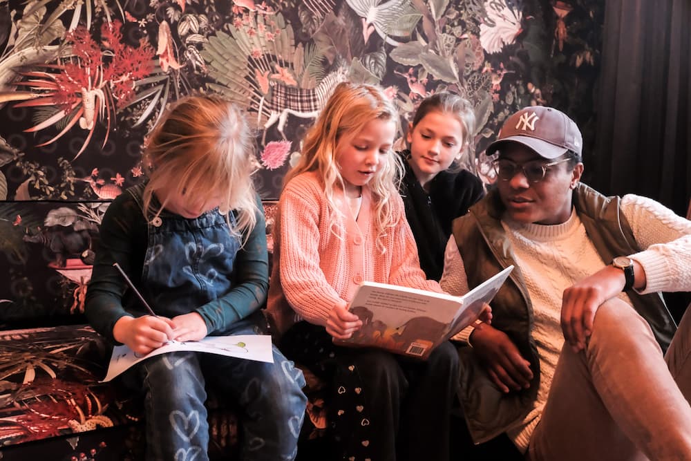 Een volwassene en drie kinderen lezen samen.